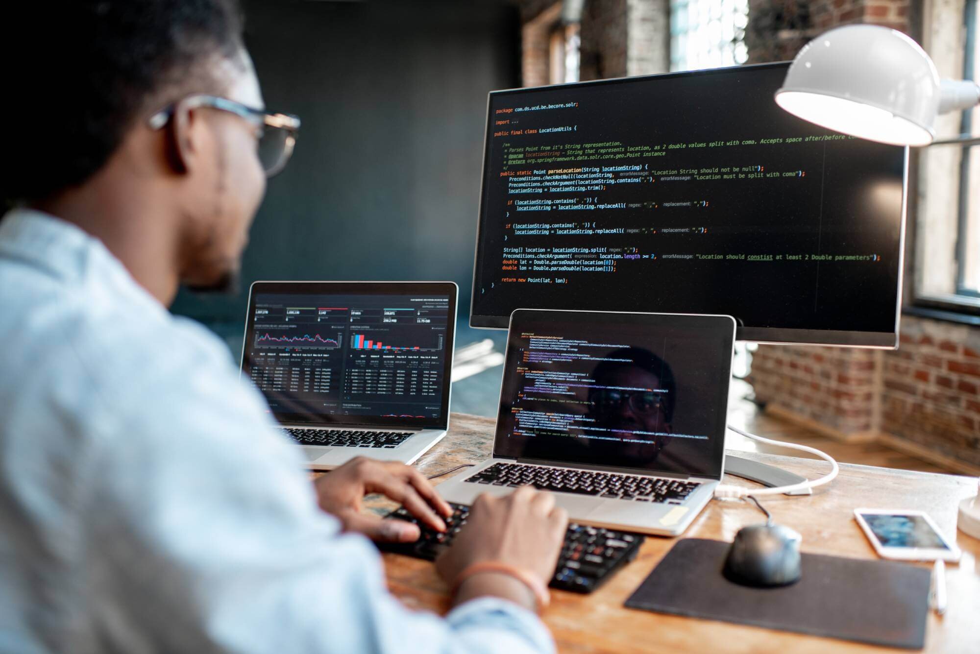 Online-Umschulung zum Fachinformatiker – Grone Online Akademie Mann arbeitet am Computer mit Programmcode auf mehreren Bildschirmen – Online-Umschulung in Informatik