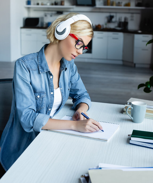 Online-Weiterbildung Frau mit Kopfhörern lernt online und macht Notizen für eine Weiterbildung